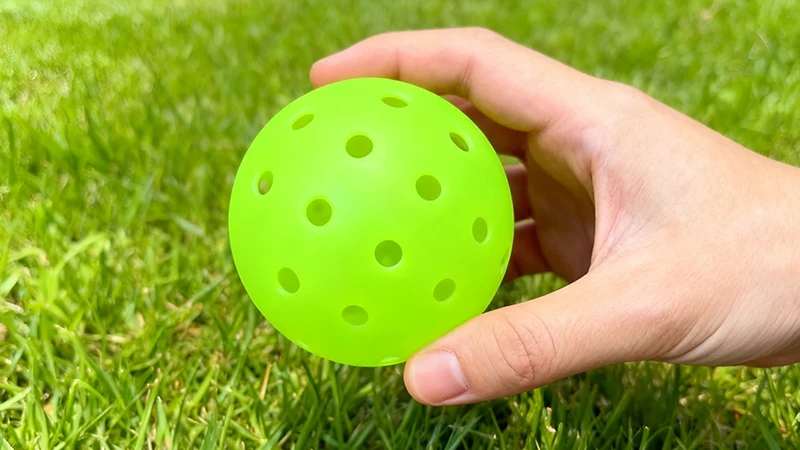 holding a pro 48 holes pickleball ball - 1